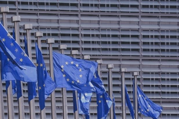 Powiewające na masztach flagi Unii Europejskiej. Flagi w kolorze niebieskim z dwunastoma gwiazdkami ułożonymi w kształcie okręgu.