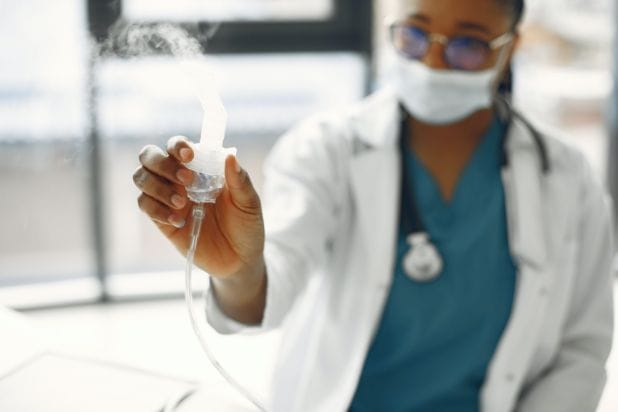 Nebulizator trzymany w ręku przez medyka.