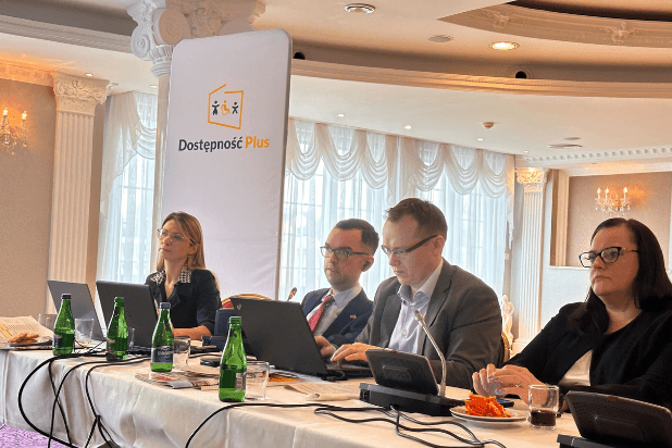 Adrian Furman, minister Jarosińka-Jedynak i dwóch innych uczestników przy stole panelistów, za nimi baner promocyjny Programu Dostępność Plus