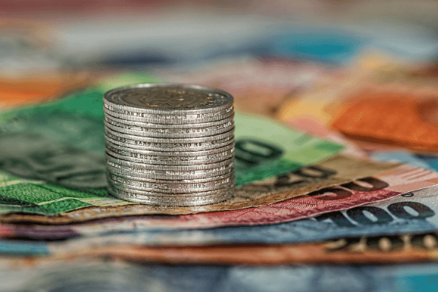 stos monet, w tle banknoty Euro o różnych nominałach